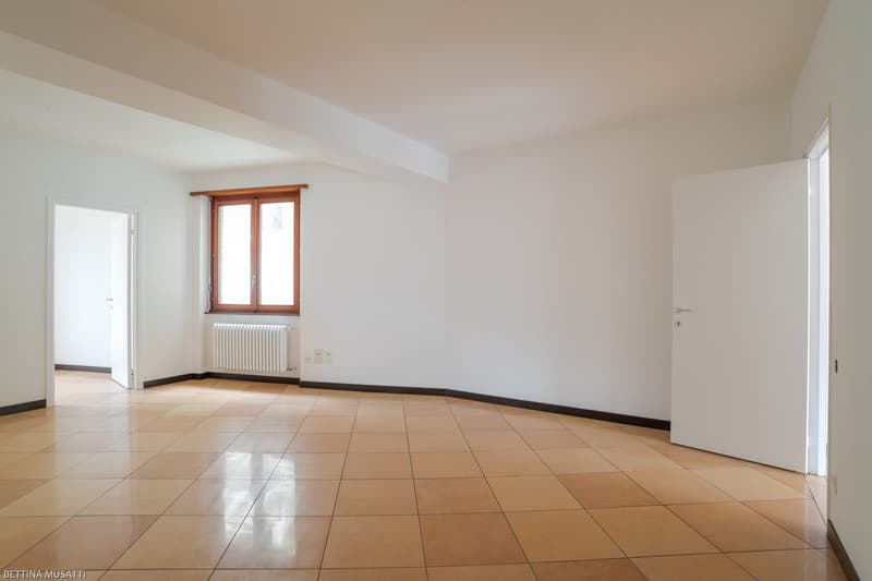 empty room, brown tiled floor, white walls, windows, radiator