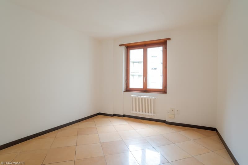 empty room with tiled floor, white walls, radiator, power outlets