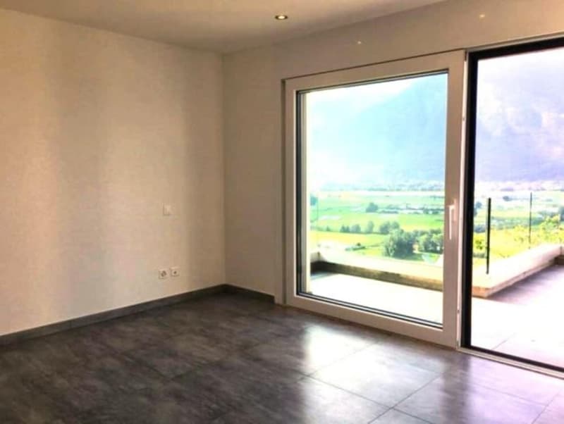 Empty room, glass sliding doors leading to balcony, tiled floor, electric outlets, no furniture