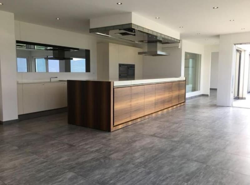 Open kitchen with white cabinets, wooden countertop, island, modern appliances, tiled floor