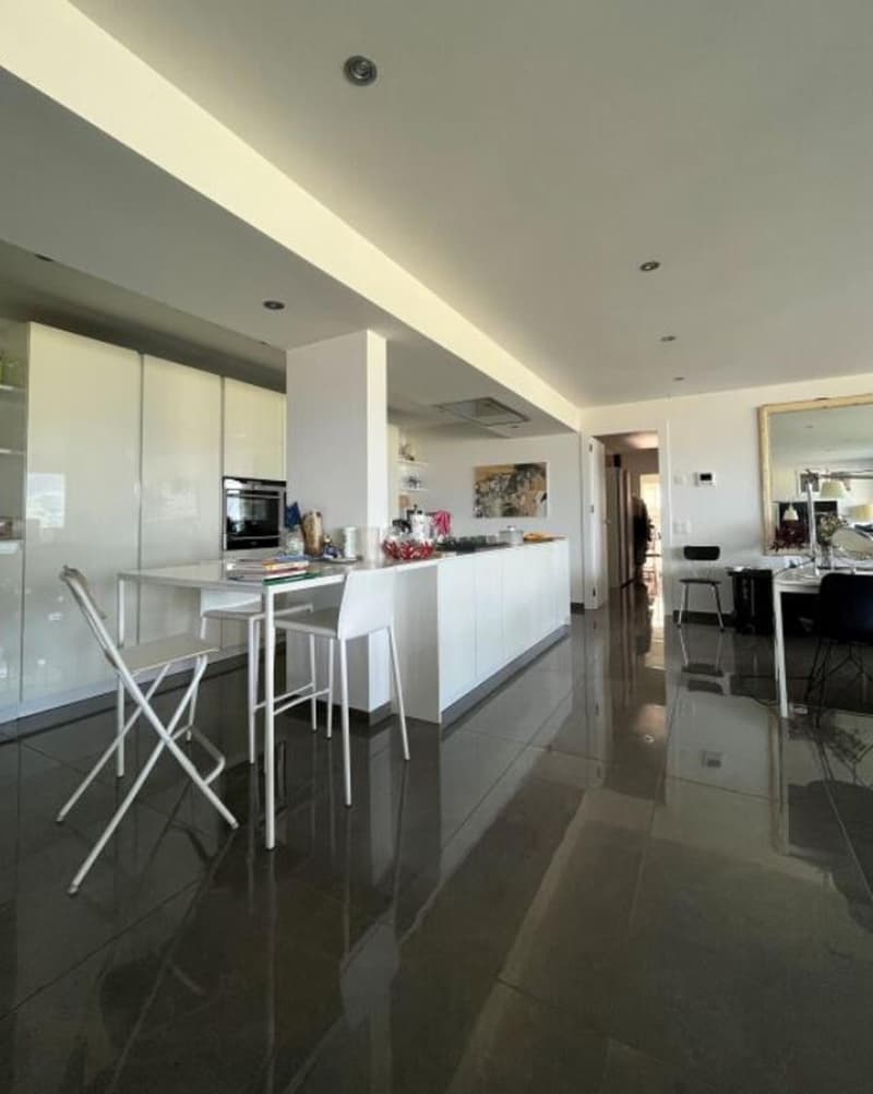 modern kitchen, white cupboards, island with a dining table, white table and chairs, oven and dishwasher built-in, white flooring, white ceiling