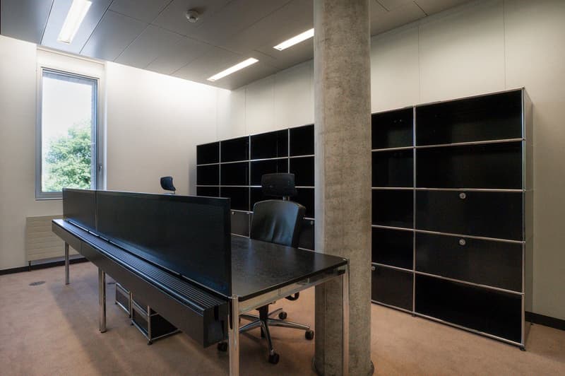 modern office space with large windows, black tables, chairs, and shelves