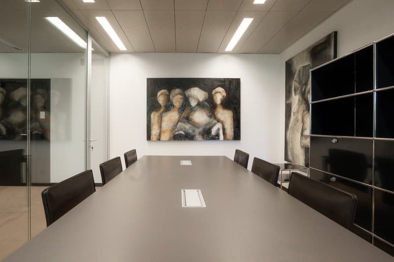 long table, black leather chairs, white walls, 3 paintings, ceiling lights