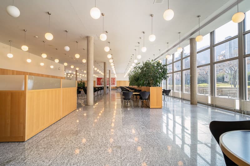 long cafeteria, tables and chairs, hanging lamps, windows