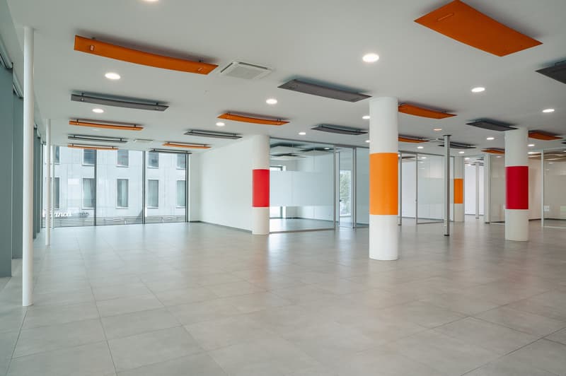 modern open space, square tiles, orange and white pillars, large windows, air vents on ceiling