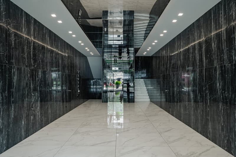 white tiled floor, black marble walls, white ceiling, central staircase