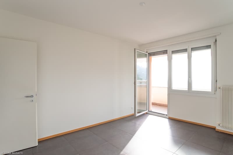 tiled floor, sliding glass door, balcony, white walls, closed door, windows