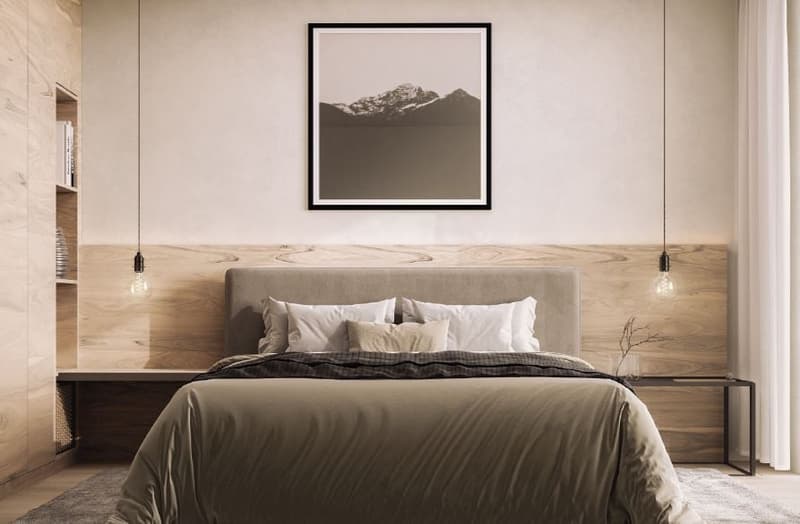 large bed with gray coverlet and multiple pillows, two nightstands, hanging lamps, mounted frame, carpet, wall with wooden panels, open shelf with books
