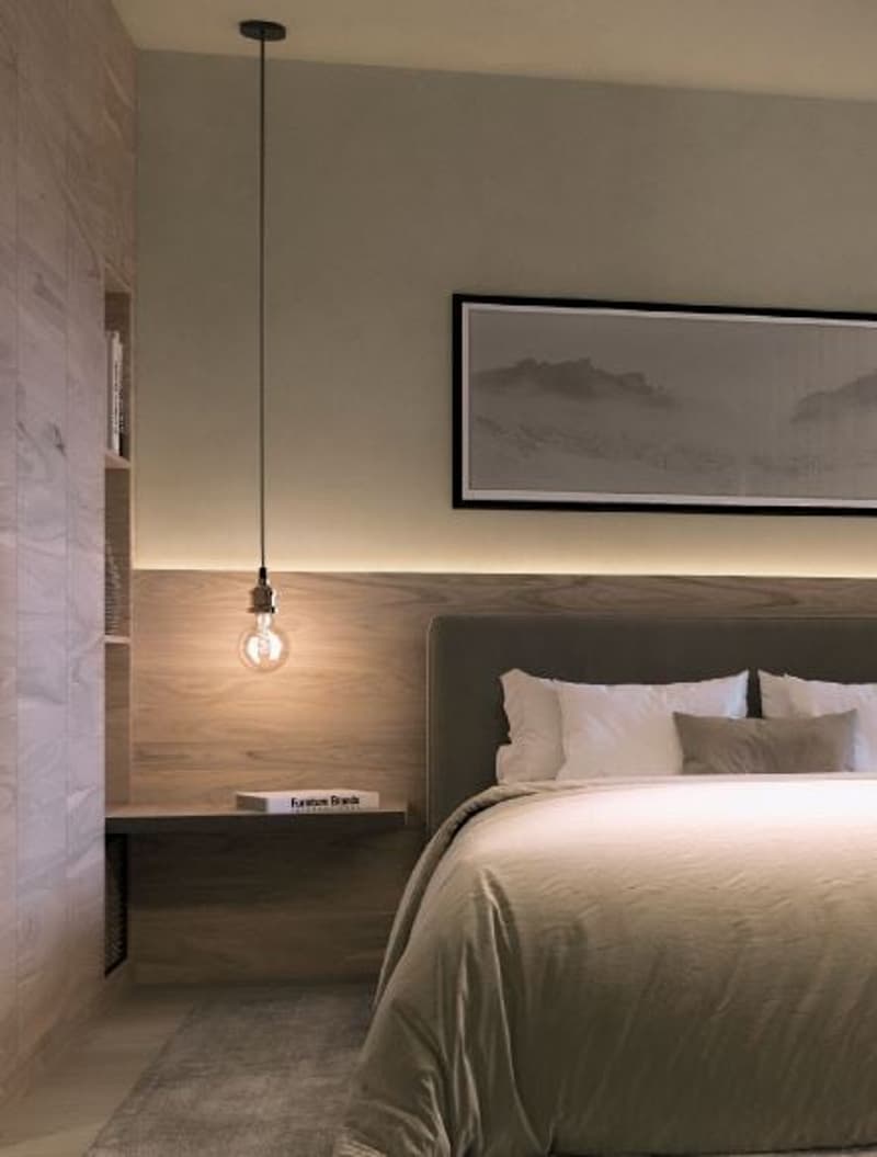 Modern minimalist bedroom with wooden walls and flooring, large bed, bedside table with book, frame on the wall above the bed, pendant lamp