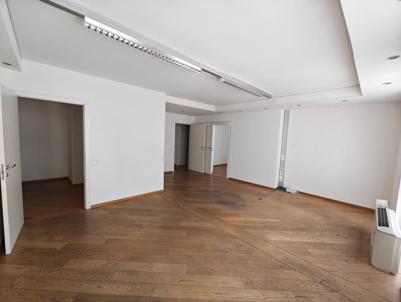 empty room, white walls, wooden floor, ceiling light, open doors, an air conditioner