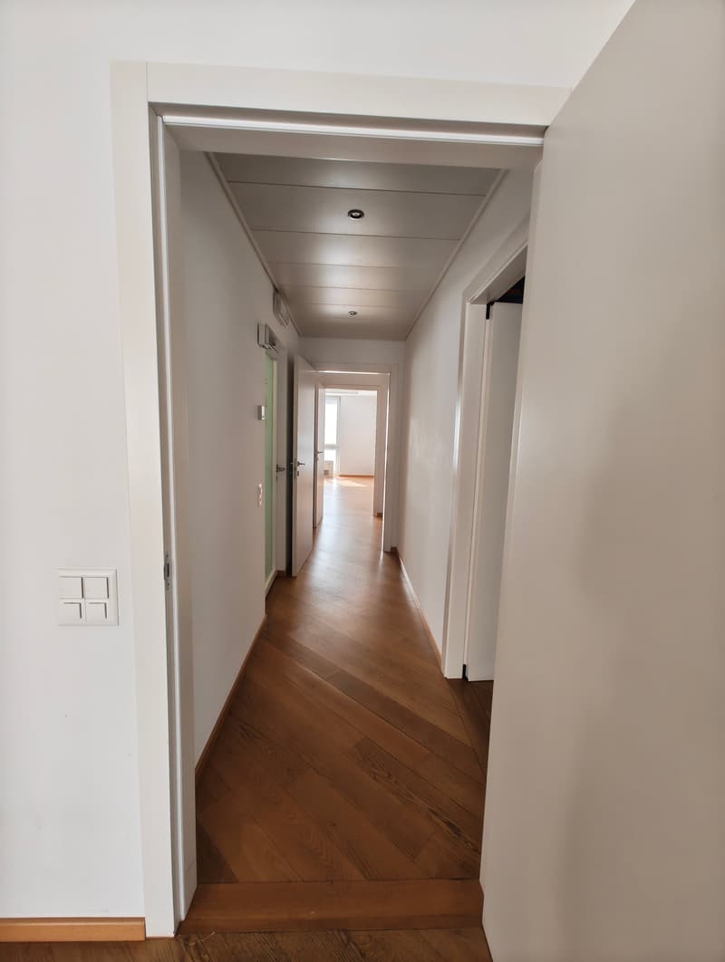 wide wooden hallway with white walls and ceiling