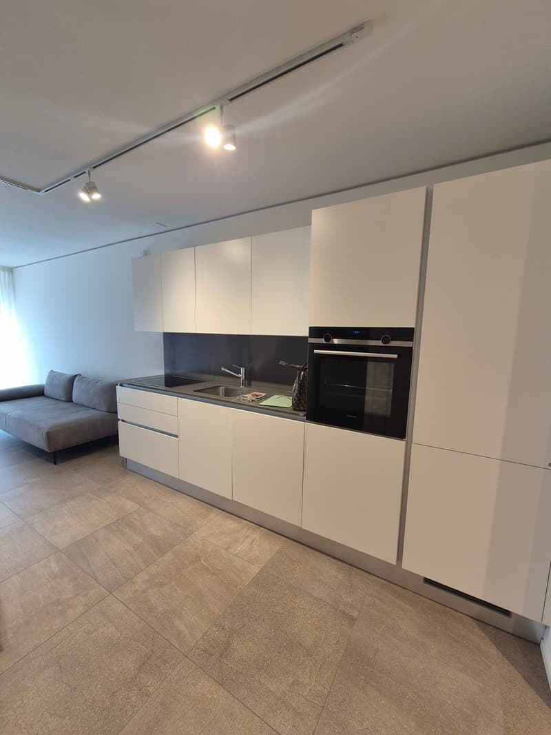 modern kitchen with white cabinets, stainless steel sink, oven, and tiled floor
