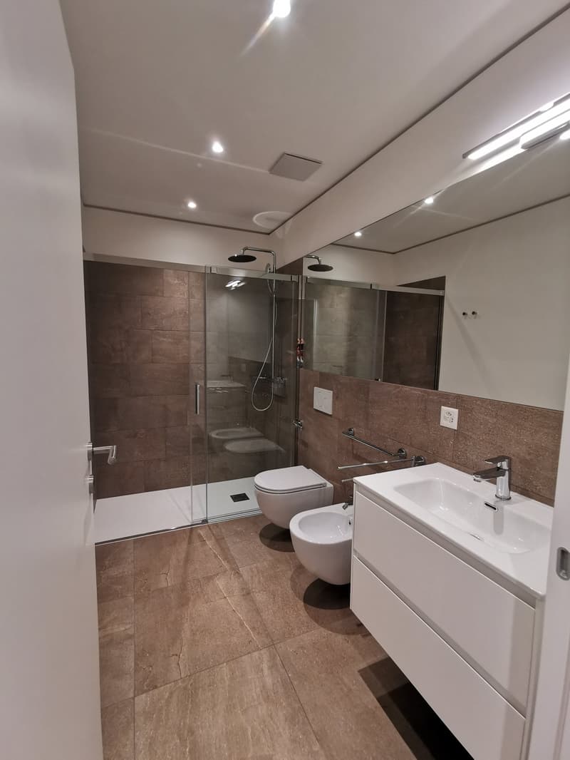 Bathroom with walk-in shower, bidet, and toilet, with a vanity and mirror