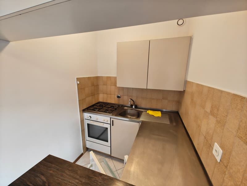 small kitchen with white appliances, tiled backsplash, stainless steel countertop, white cabinets, gas stove, oven, sink, faucet