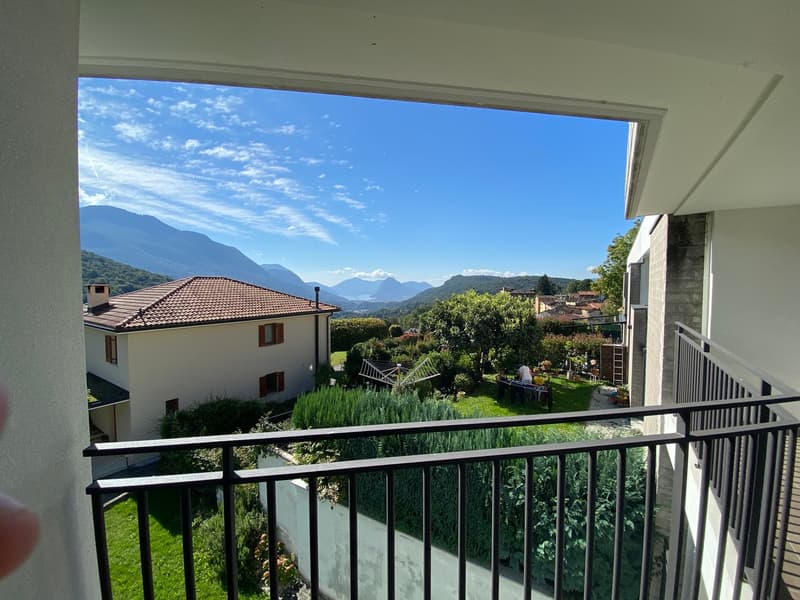 Balcony with railings, view of a house, garden, and mountain range in the distance