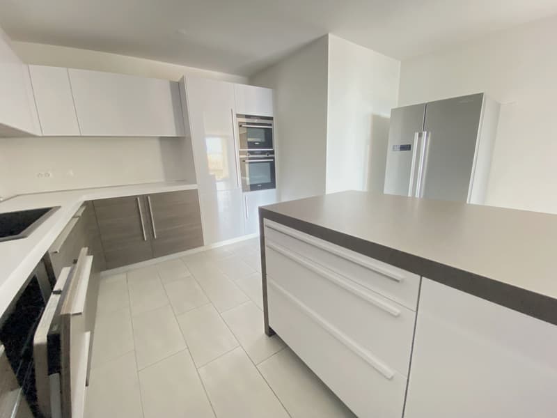 modern kitchen, white cabinets, tiled floor, stainless steel appliances, double oven, refrigerator, island countertop, gray sink countertop