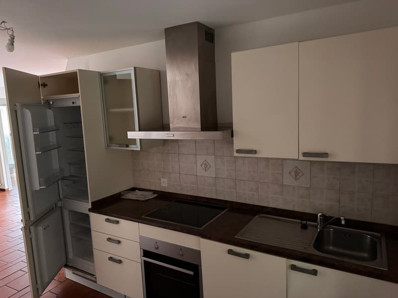 Open kitchen with refrigerator, oven, hob, sink, and a large window providing a view.