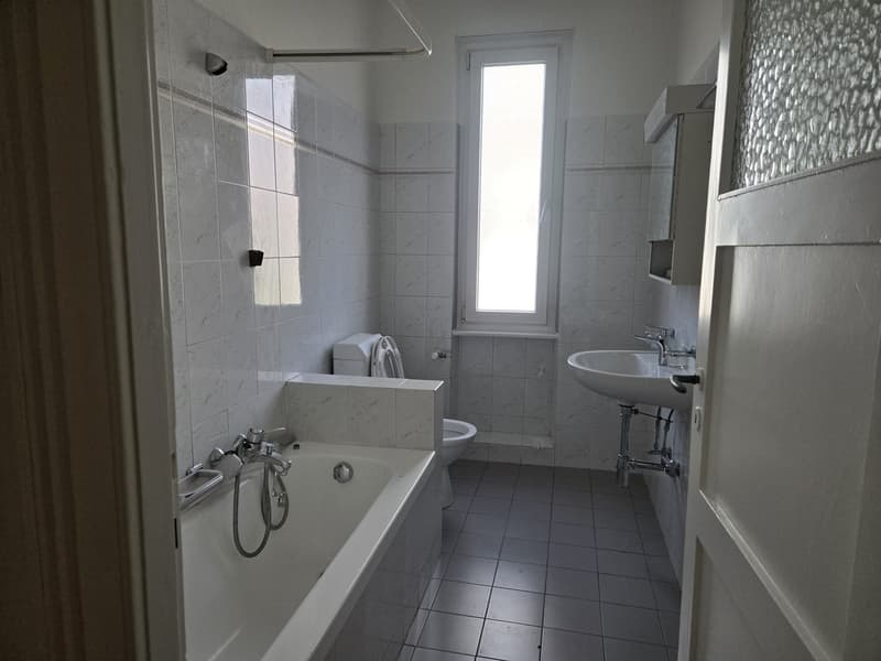White tiles, bathtub, sink, toilet, window