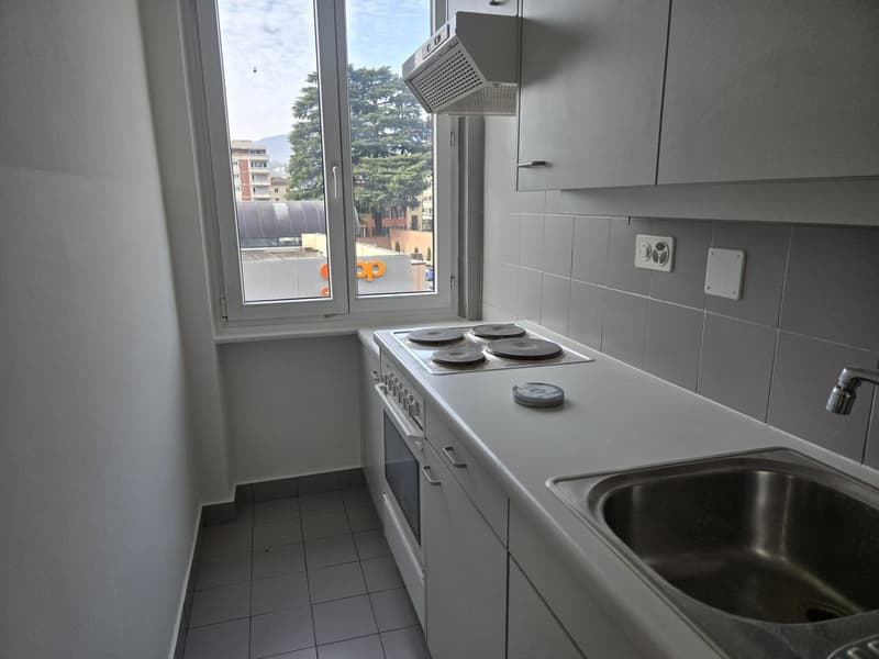 modern kitchen with windows, gas stove, oven, tile floor, white cabinets, white sink, stainless steel sink