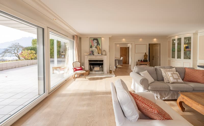 Spacious living room with large windows, wooden floor, fireplace, and modern furniture.