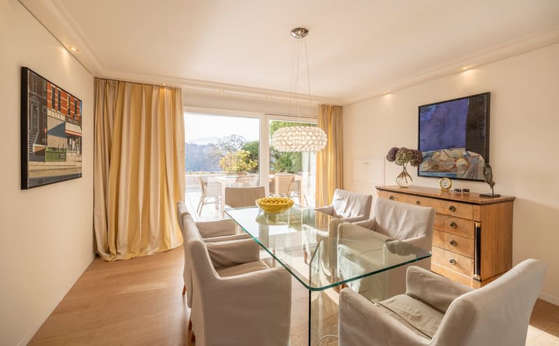 Modern dining room with glass table, white chairs, and a view of the outdoors.