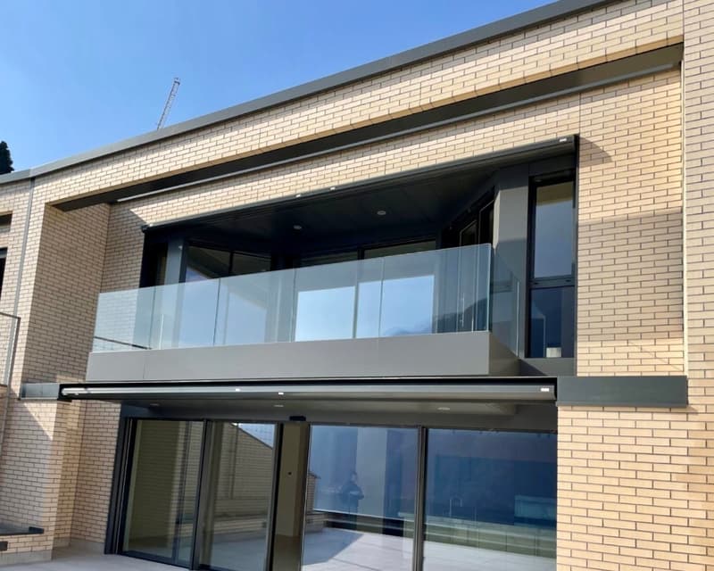 Modern commercial building with a brick facade, large glass windows, and a balcony or terrace on the upper level.