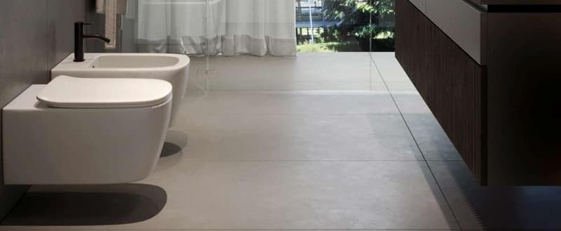 modern bathroom with white fixtures, glass shower enclosure, white tiled floor, white walls, and a window with white curtains