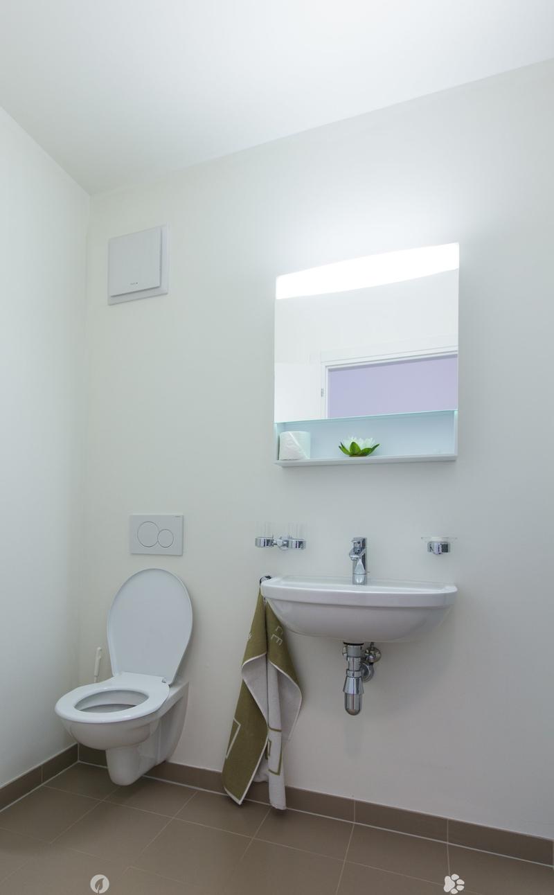 White toilet, sink with faucet, wall-mounted cabinet, tiled floor