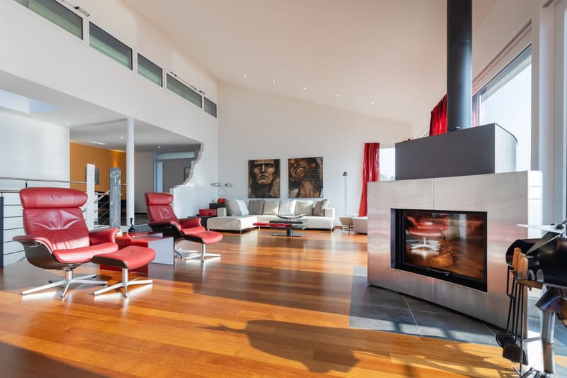Fireplace, hardwood floor, red recliners, red armchairs, coffee table, red cushions, large windows, red curtains