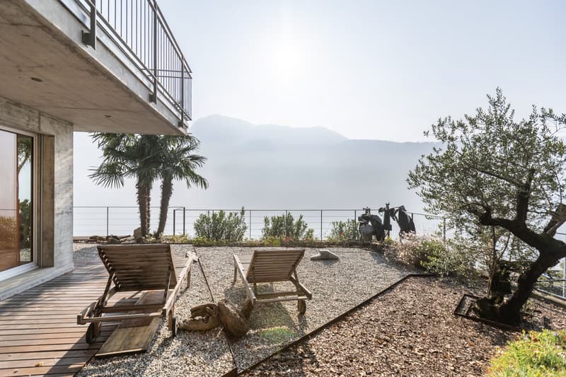 Outdoor wooden lounge chairs, pebble path, trees, overlooking mountains and water