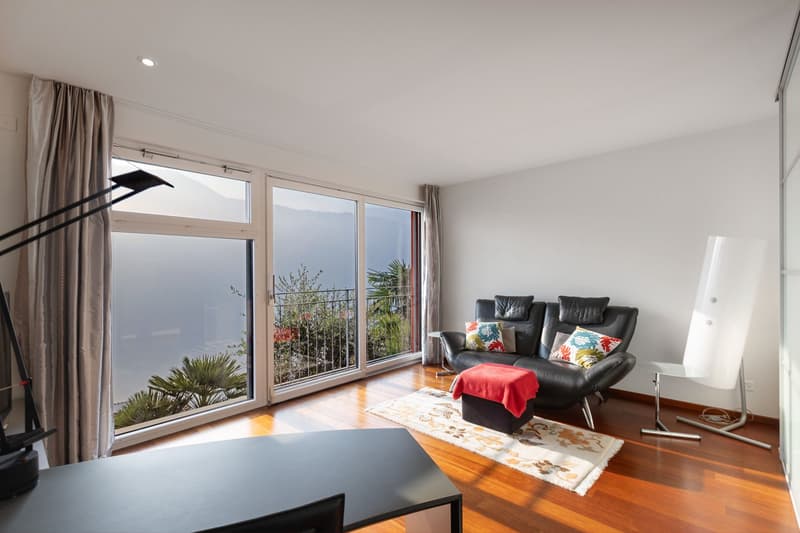 modern style, hardwood floors, black leather sofa, large windows, balcony with railing, rug, desk, large panoramic window