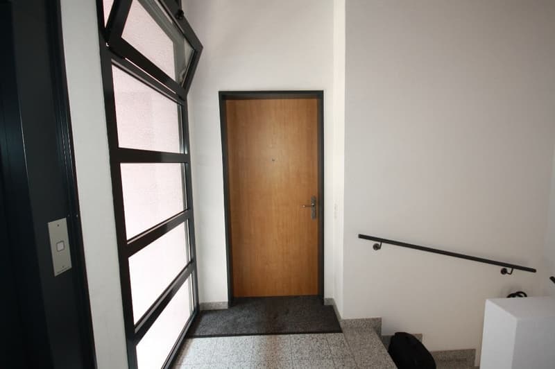 carpeted floor, wooden entrance door, large windows, stairs