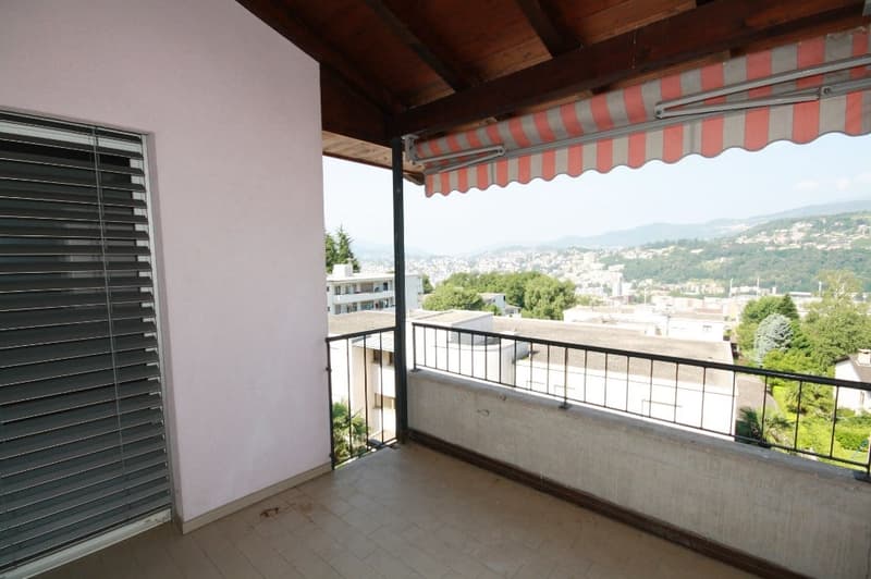 empty balcony with tiled floor, wooden awning, and a view of the city