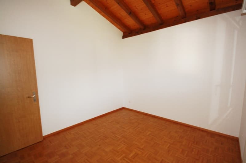 Empty room with wooden floor, white walls, and wooden door