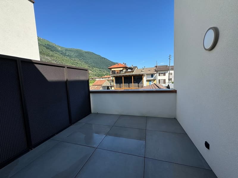tiled floor, enclosed balcony, small outdoor lamp, distant buildings, mountains