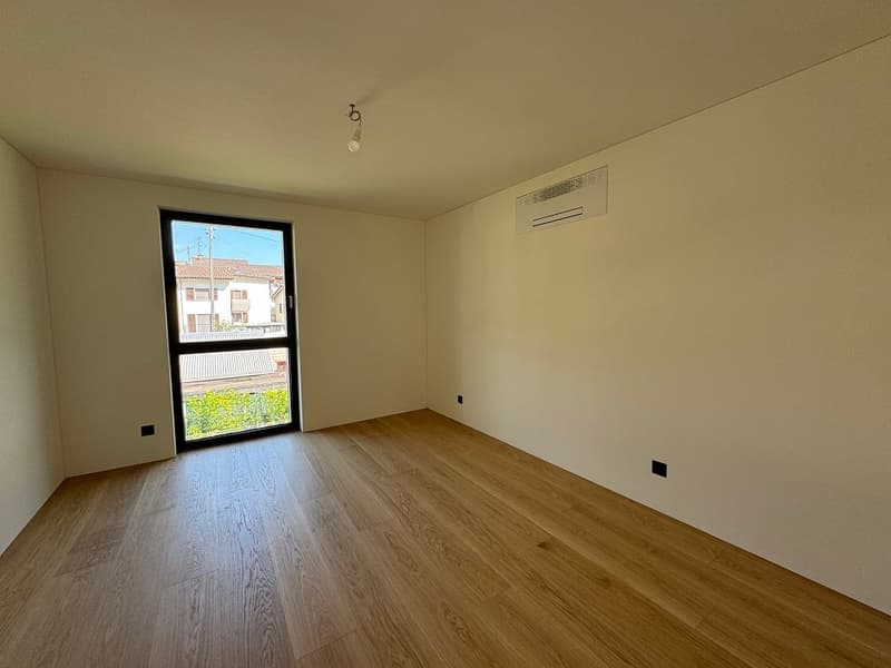Empty room with hardwood floors, large window, mounted air conditioning unit, ceiling light