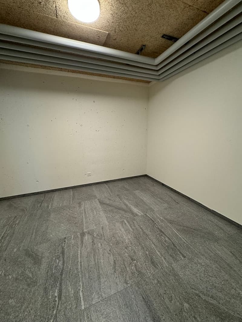an empty room with gray floor and white walls