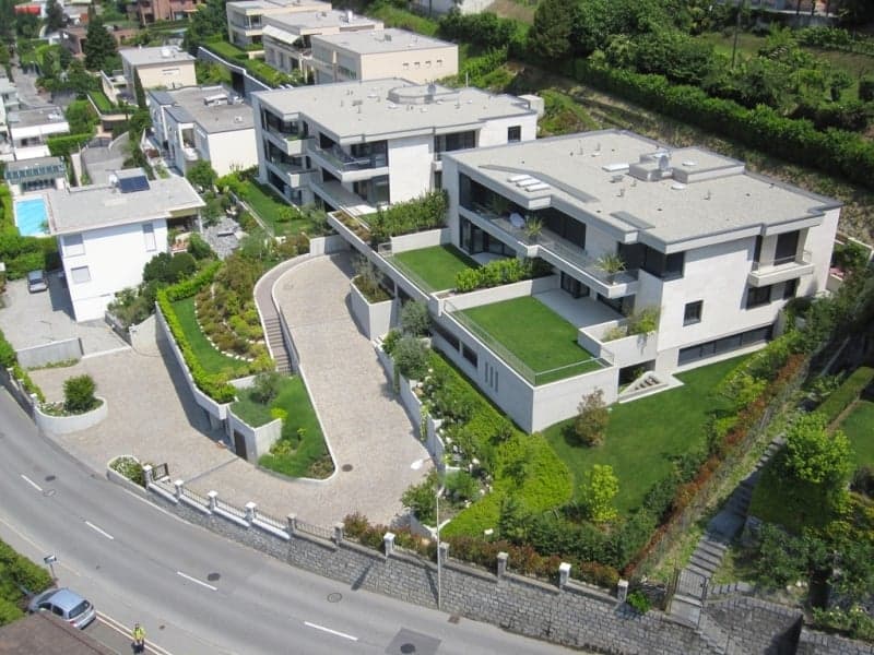 Modern apartment complex with swimming pool, green lawns, and a scenic view