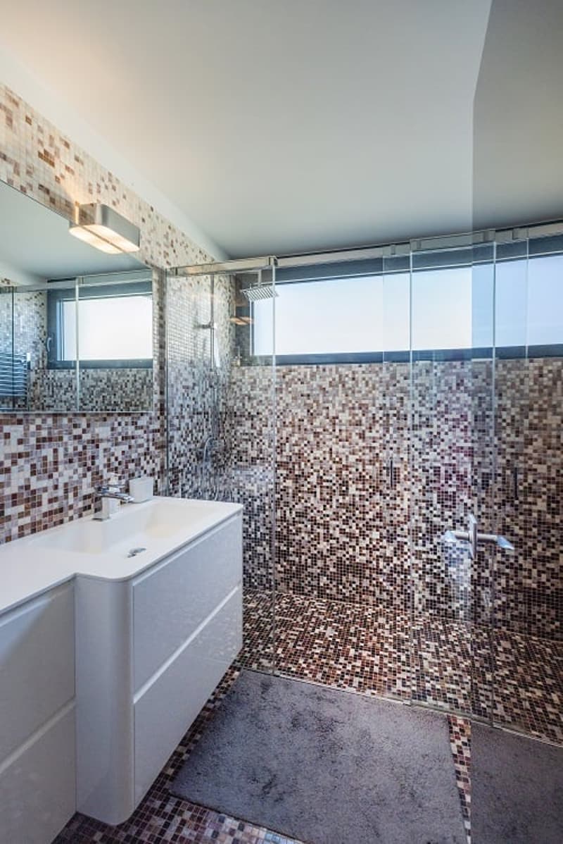modern bathroom with white sink, mirror, and tiled walls