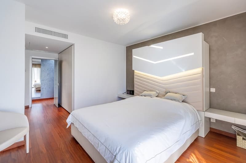modern design, white walls, wooden floor, large bed, white headboard, bedside tables, white chair, chandelier