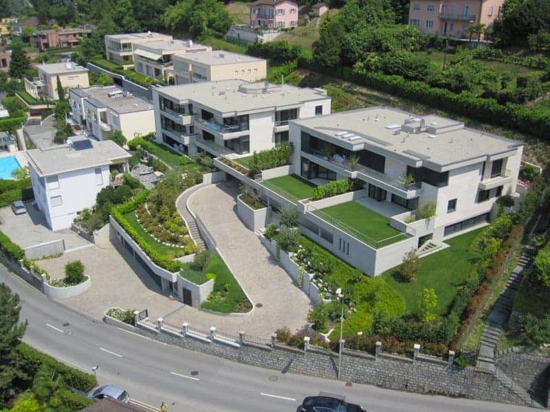 Modern apartment complex with swimming pool, green gardens, and a scenic view