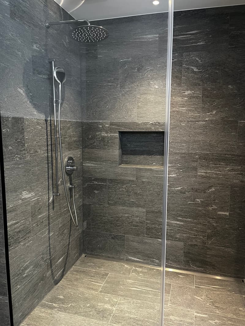 shower area with shower head and hand shower, shower wall with niches, tiled floor and wall