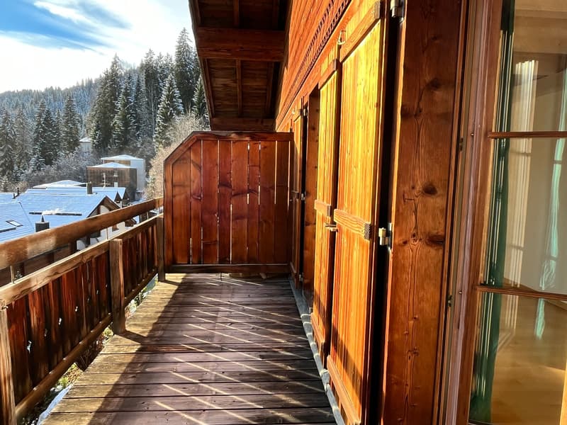 large wooden balcony with railings, wooden walls, clear sunny day, view of the mountains