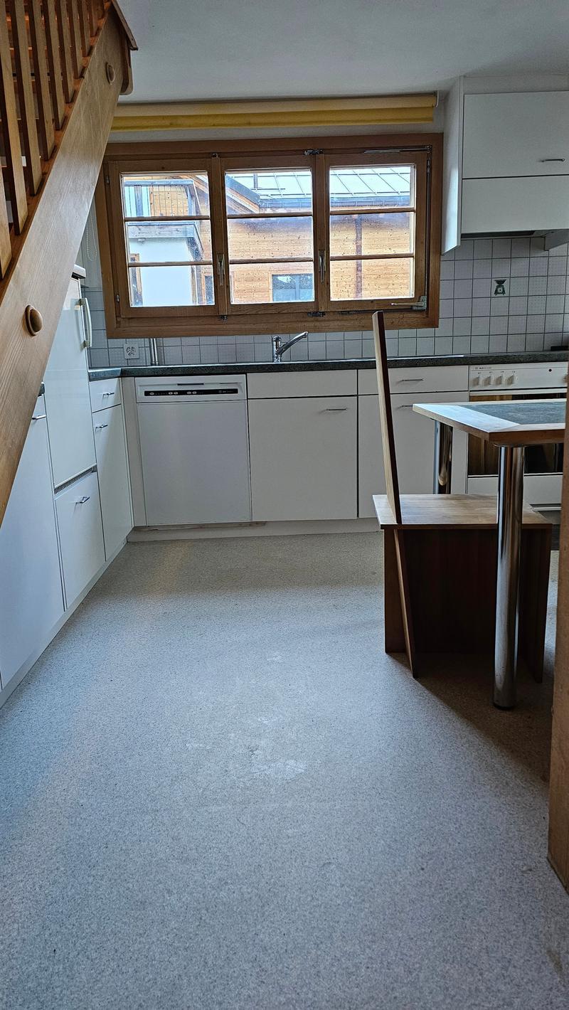 Kitchen area with sink, dishwasher, cabinets, and a wooden table