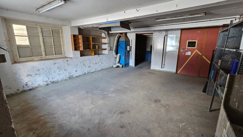 Concrete floor, window, shelves, large pipes, industrial machines, large doors, metal racks