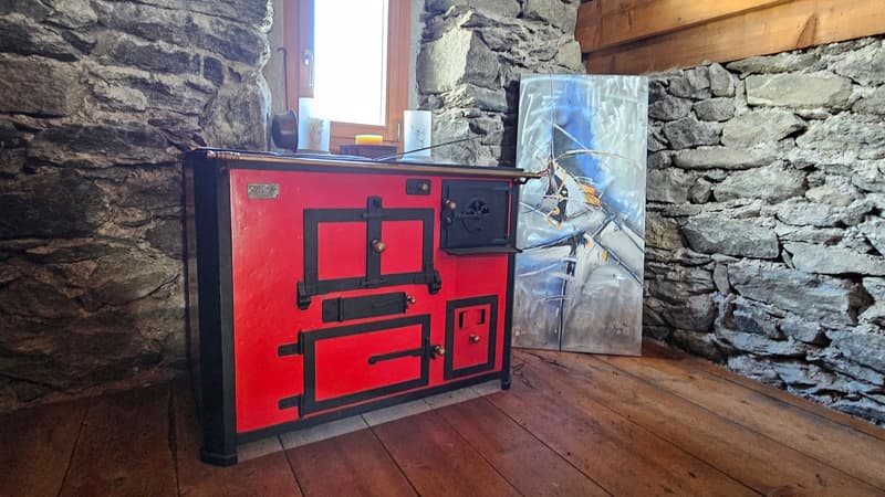 a red fireplace against a stone wall, a painting on the wall, wooden floor