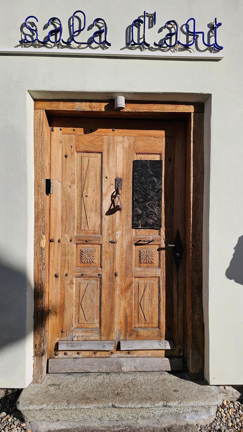 Front door of wooden house with blue sign reading 'Sala d'art'.