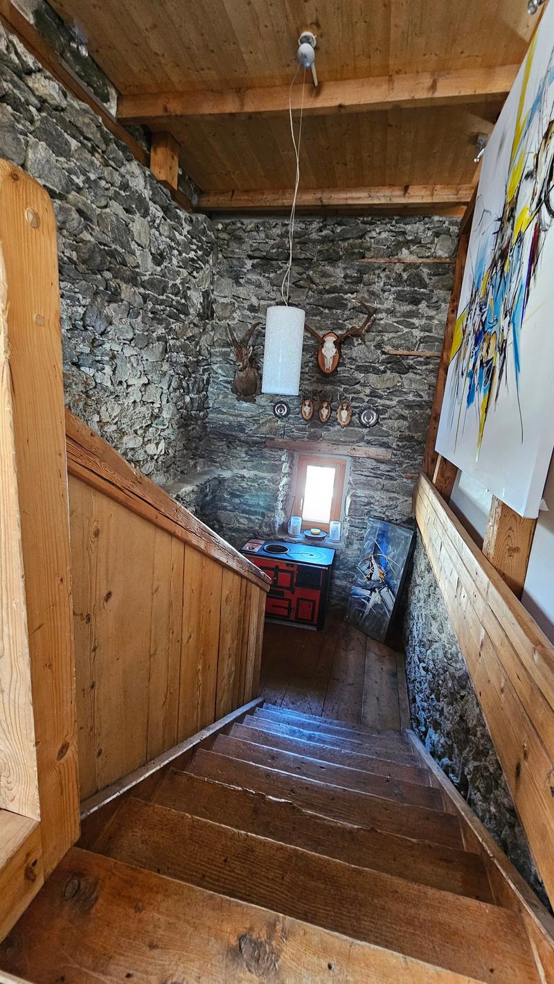 Wooden stairs with wood sides and bottoms. The top side has wood beams. A small table with two cups and a lamp can be seen. There is a wall lamp hanging from the ceiling.