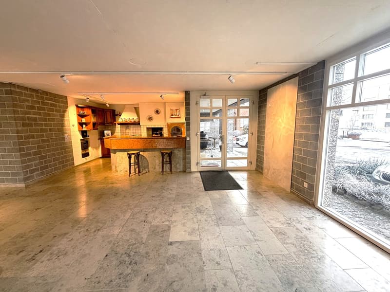 wide entrance hall with marble tiles, brick wall, open kitchen with wooden bar and island, sliding door to outside, 2 bar stools, double doors, open kitchen with oven, fridge, cabinets, countertop, large windows, outdoor table and grill, parked car