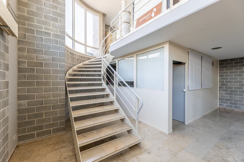 stairwell, spiral staircase, tile floor, glass windows, brick walls